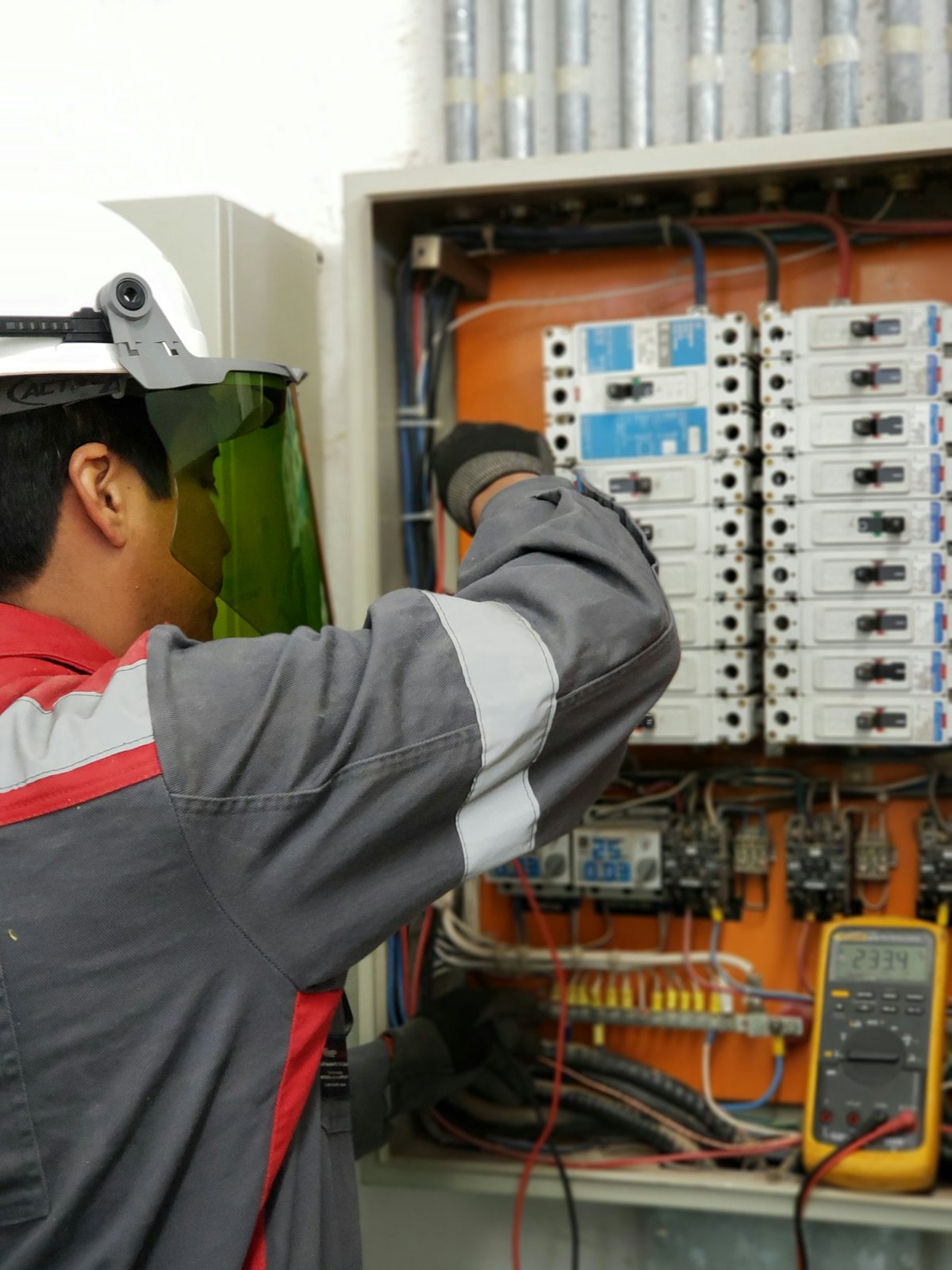 An electrician testing a distribution board with a multimeter.