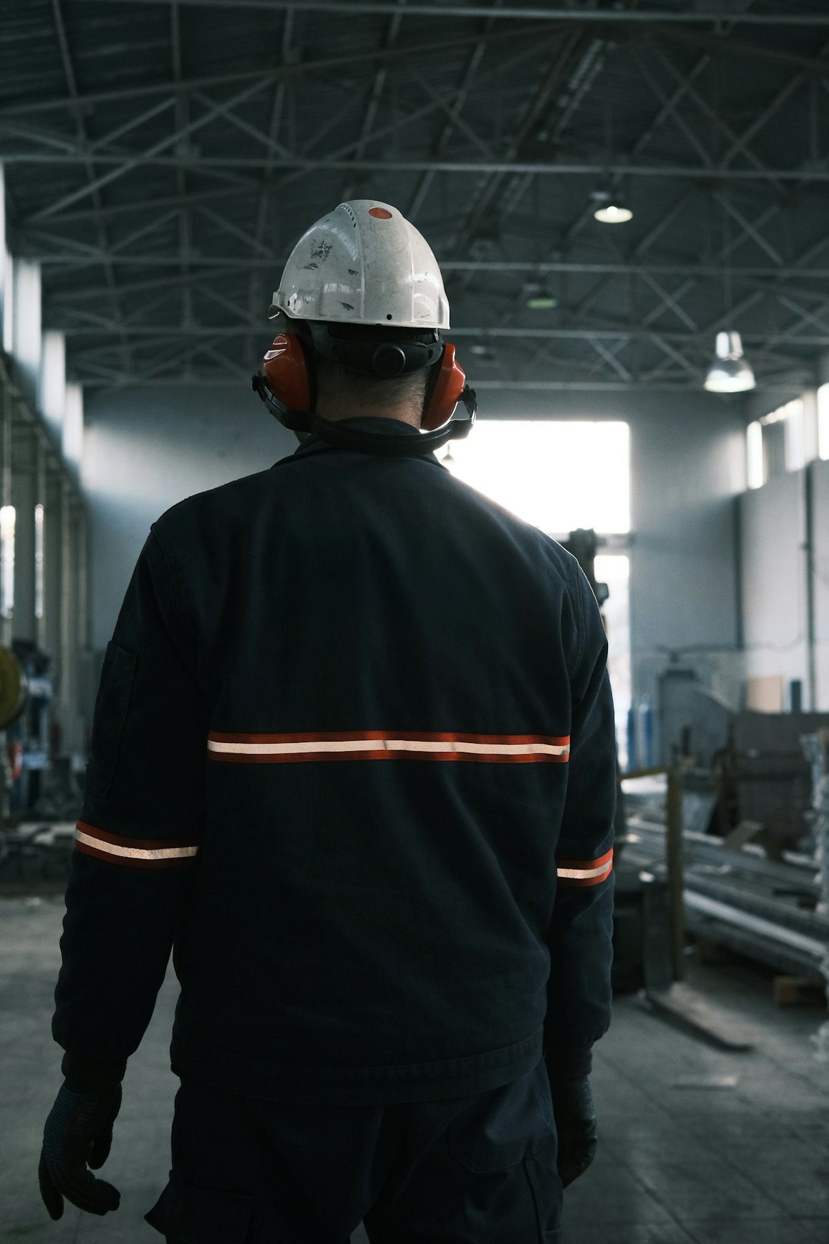 A facilities technician in a hard hat walking through a plant room.