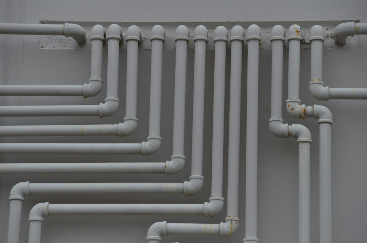 A grid of water pipework running across a plant-room wall.